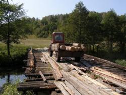 Трактор с бревнами на деревянном мосту